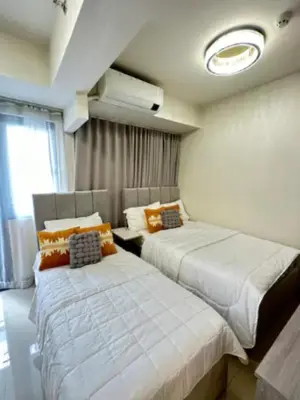 a bedroom with two beds and a window at Sweet Escape at S Residences in Manila