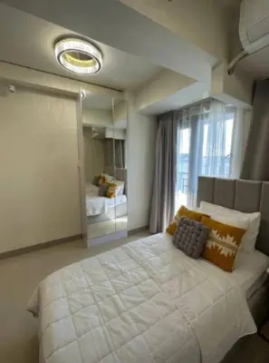 a bedroom with a large white bed and a mirror at Sweet Escape at S Residences in Manila
