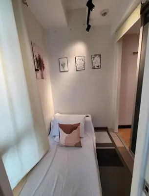 a small bedroom with a white bed with a pillow at Stunning Suite 10 Steps from Eastwood Mall in Manila