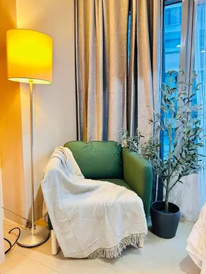 a green chair sitting in front of a window at Kozy Mood Studio in Manila