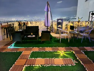 a rooftop patio with tables and chairs and an umbrella at Spectacular Penthouse with Stunning Balcony in Eastwood Mall in Manila
