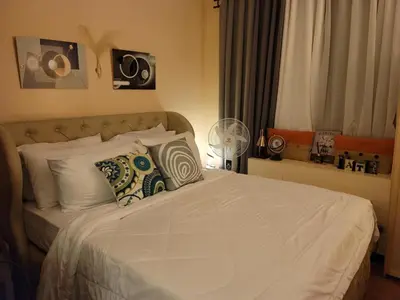 a bedroom with a bed with white sheets and pillows at Spectacular Penthouse with Stunning Balcony in Eastwood Mall in Manila