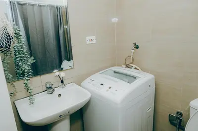 a bathroom with a sink and a washing machine at Budget staycation near moa in Manila