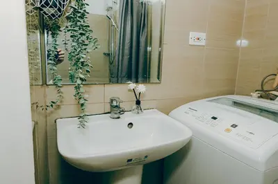 a bathroom with a sink and a washing machine at Budget staycation near moa in Manila