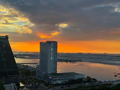 a tall building with a sunset in the background at 640 Coffee Room Shore 2 Residences MOA Pool View by Prime Stay in Manila