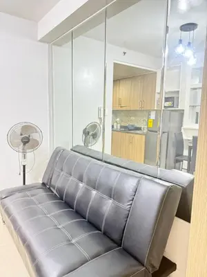 a leather couch in a living room with a kitchen at Shore 1 residences Tower D Pasay City in Manila