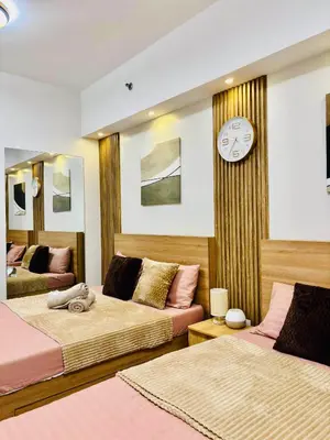 a bedroom with two beds and a clock on the wall at Shore 2 Residences Tower 1 in Manila