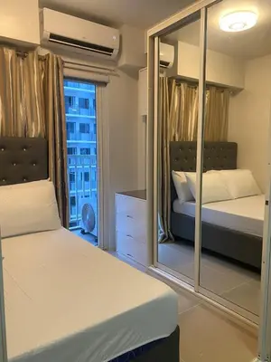 a bedroom with two beds and a large mirror at Shore 1 Residences Tower D Pasay in Manila