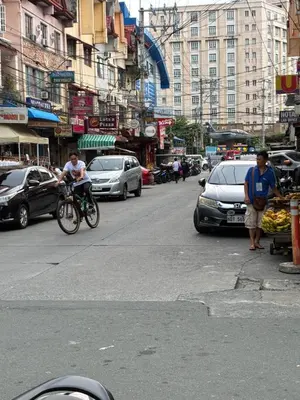 a man riding a bike down a busy city street at Cozy Haven Across Terminal 3 in Manila