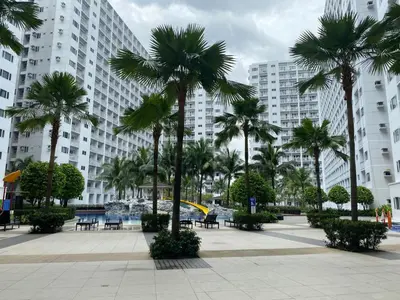 a courtyard with palm trees in front of a building at Shore 1 Spacious Smart Home 3C in Manila