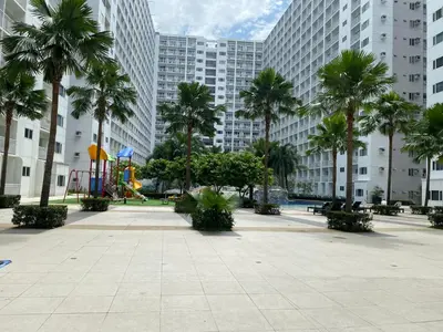 a park with a playground and palm trees and buildings at Shore 1 Spacious Smart Home 3C in Manila