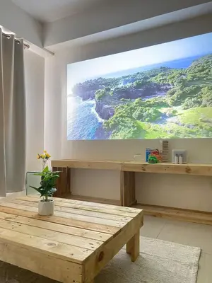 a large screen in a room with a wooden table at 2BR walking distance to MOA - near PICC,NAIA,STAR CITY by JBCO Staycation Jha in Manila