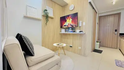 a living room with a couch and a fire on the wall at 1 Bedroom Apartment in Pasay near MOA in Manila