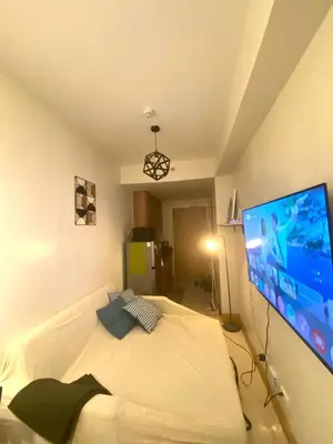 a bedroom with a bed with a large tv on the wall at Cabin and a cozy stay near MOA in Manila