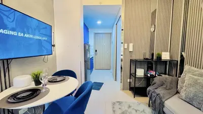 a living room with a white table and blue chairs at 2 Bedroom Rental Apartment in Pasay in Manila