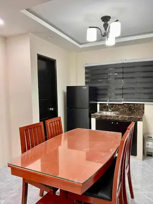 a dining room table with chairs and a black refrigerator at Apartment Taguig Makati staycation with parking in Manila