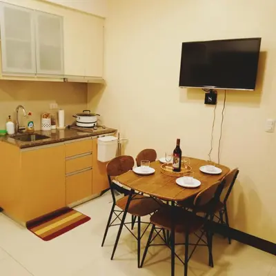 a kitchen with a table with chairs and a television at The Viceroy Tower Staycation at McKinley Hills Taguig in Manila
