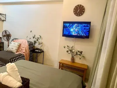 a living room with a clock and a tv on the wall at Captivating Crib in the Metro in Manila