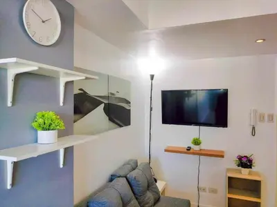 a living room with a couch and a tv and a clock at Azure Place Maui 8th floor in Manila