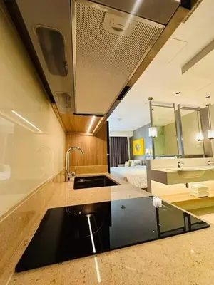 a kitchen with a sink and a living room at Novotel Rockwell View Hotel Residences in Manila
