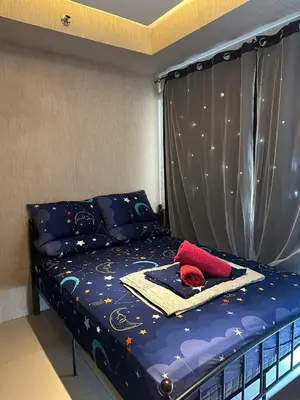 a bed with a blue comforter and a red hat on it at Jeric Place Staycation in Manila
