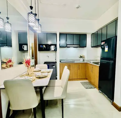 a kitchen with a table and chairs and a black refrigerator at Jolgeous Staycations and Rentals in Manila