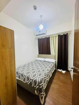 a bedroom with a bed in a room with a window at Jolgeous Staycations and Rentals in Manila