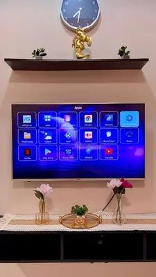 a television on a wall with a clock and flowers at Aura Zen Suites condotel in Manila