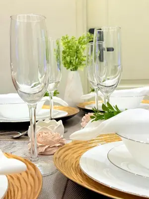 a table with wine glasses and plates on it at 1-Bedroom Cozy Haven Sorrento Oasis in Manila