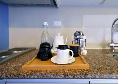 a wooden cutting board with cups and mugs on a kitchen counter at Starwars Retreat Gaming & 84 inch Movie & Near Mall in Manila
