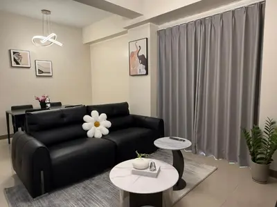 a living room with a black couch and a table at HomeMadeLuxury 3 Bedrooms Seaview Sunset View Near Manila Airports Okada MOA in Manila