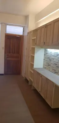 an empty kitchen with wooden cabinets and a door at Nemar Ladies Dormitel in Manila
