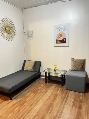 a room with a bed and a couch and a table at Staycation in Alabang in Manila