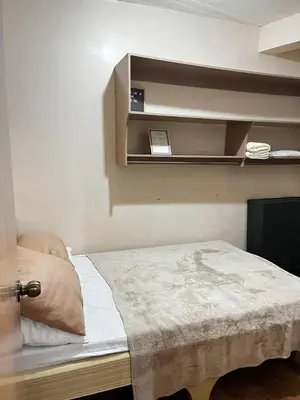 a small room with a bed and shelves on the wall at Staycation in Alabang in Manila