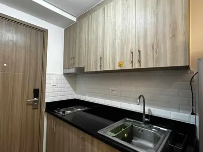 a kitchen with a sink and wooden cabinets at Cozy MOA Condo Perfect for 2 in Manila