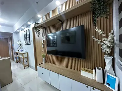 a living room with a large television on a wall at Shore 3 Residences with WiFi, Balcony, Pool in Manila