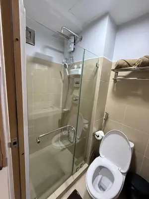a bathroom with a toilet and a glass shower at Shore 3 Residences with WiFi, Balcony, Pool in Manila