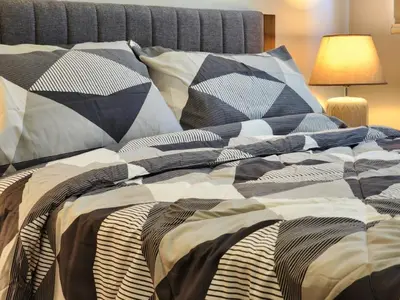 a bed with a comforter and pillows on it at Modern 1 br in Park Mckinley West with Breathtaking view fast internet in Manila