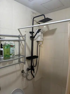 a shower in a bathroom with a toilet and shelves at Mariz Suites in Manila