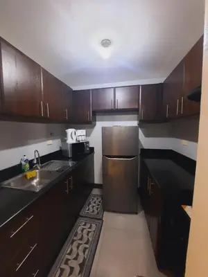 a kitchen with wooden cabinets and a stainless steel refrigerator at Mariz Suites in Manila