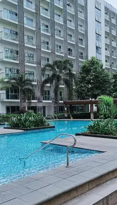 a swimming pool in front of a large building at Dreamy Condotel Across NAIA Terminal 3 in Manila