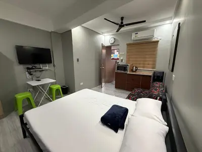 a bedroom with a large white bed and a kitchen at Studio Room near Circuit Makati in Manila