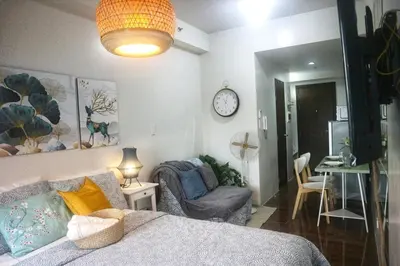 a bedroom with a bed and a chair and a clock at Calming Haven at City Center with Netflix and Hi-Speed Wi-Fi in Manila