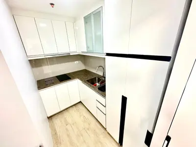 a small kitchen with white cabinets and a sink at Stylish Luxe Apt in Gentry Manor in Manila