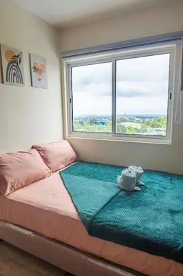 a bed in a room with a large window at Family-Friendly 2BR Staycation near Nuvali & Enchanted Kingdom in Puting Kahoy
