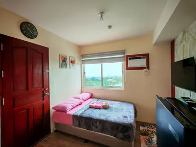 a bedroom with a bed with pink pillows and a window at Family-Friendly 2BR Staycation near Nuvali & Enchanted Kingdom in Puting Kahoy