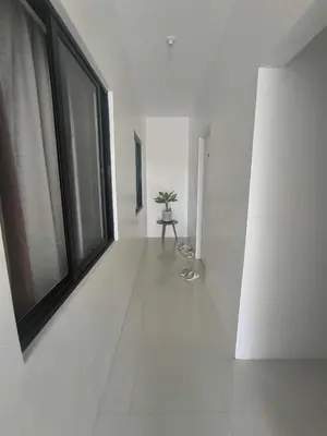 a white hallway with a window and a table with a plant at Yujia Apartment in Manila