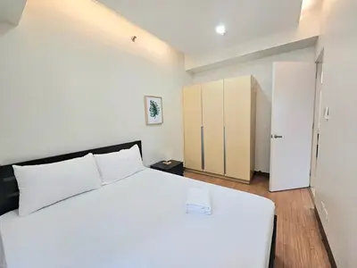 a bedroom with a large white bed and a closet at The Infinity Towers in BGC - Spacious 2 Bedroom - View, Washer, Fast WiFi in Manila