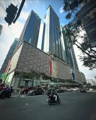a man riding a motorcycle down a street with tall buildings at BGC 1BR with Fast wifi and Pool use in Manila
