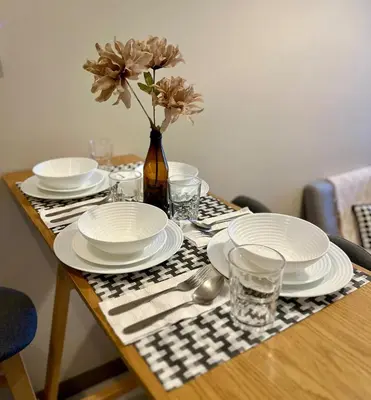 a table with plates and glasses and a vase with flowers at BGC 1BR with Fast wifi and Pool use in Manila
